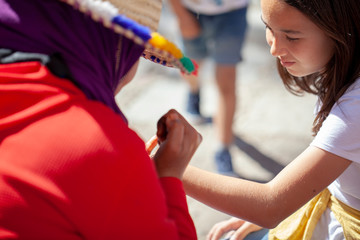 Lugareña marroquí dibujando un tatuaje con henna en la mano de una niña