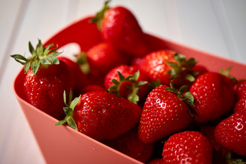 Close up of fresh juicy red strawberries in container on white table