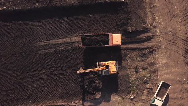 Zoom out top down view of construction site with machinery, truck, excavator.