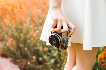 close-up photo, hand holds analog film camera on the background of a colorized flowering field the...
