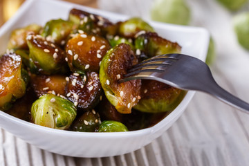 Roasted Brussels sprouts in a white bowl on a wooden background