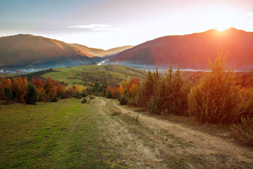 Road hiking trail in autumn colorful mountains on background of valley and magnificent sunset sky