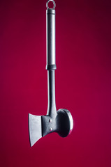 Kitchen multifunctional ax for cutting meat and forming chops on a red background.
