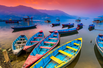 Fototapeta na wymiar Colorful Wooden Boats Parking in Phewa lake and amazing Sunset in Background,