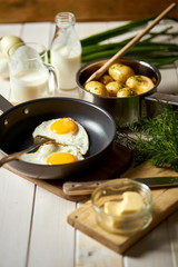 Fried egg with young potatoes with dill and milk on  wooden table