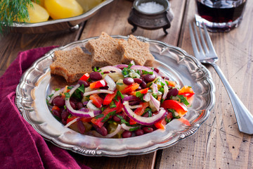 vegetarian salad with red beans and pickled cucumbers on a metal plate, horizontal