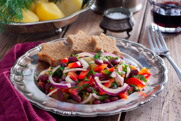 vegetarian salad with red beans and pickled cucumbers on a metal plate, horizontal