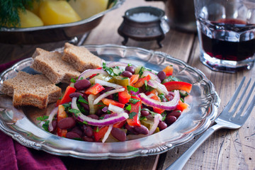 vegetarian salad with red beans and pickled cucumbers on a metal plate, horizontal