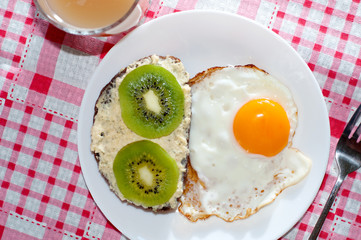 Healthy and tasty breakfast, quince juice, whole-grain bread sandwich with kiwi and egg on white plate, pink napkin