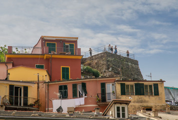 Fototapeta premium View of the colored fishermen's houses of the ancient village of Vernazza in the Cinque Terre area with tourists on the top of the medieval Castle of Doria (11th c.), Liguria, Italy
