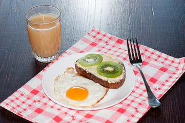 Healthy, tasty breakfast, juice, wholemeal bread sandwich with kiwi and a fried egg on white plate