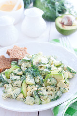 Salad with cucumbers, egg and avocado on a white plate, selective focus
