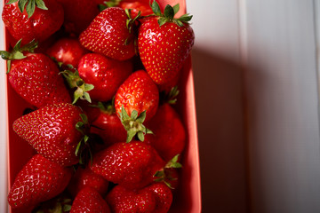 Close up of fresh juicy red strawberries in container on white table