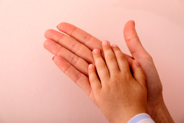 Mother uses her hand to hold her child hand.