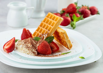 Waffles with strawberries and cream, mint and chocolate chips.
