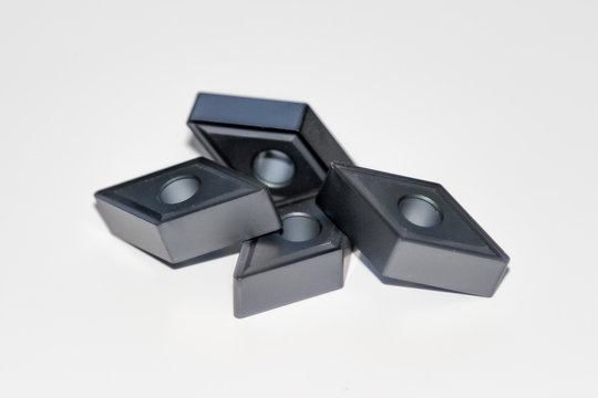 Four carbide inserts for CNC milling machine with selective focus isolated on white