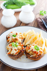 Stuffed champignons with cheese and french fries on a white plate, selective focus
