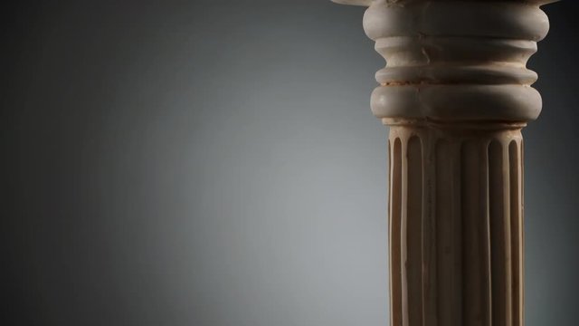 Single ancient greek column rotating slowly on gray background, copy space text area