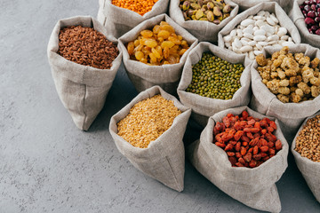 Dieting, nutrition and healthy eating concept. Colorful cereals and dried fruits rich with protein in burlap sacks. Dry legumes seeds.