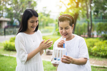 Elderly asian mother using incentive spirometer or three balls for stimulate lungs,Encouragement daughter take care and support