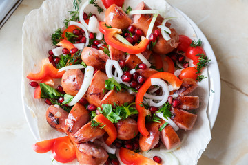 Fried sausages with vegetables on a thin flat cake in a plate. Grilled sausages with vegetables.