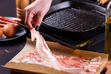 young woman in a gray apron fries bacon