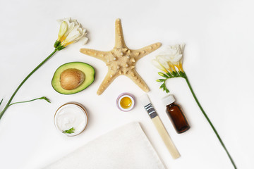 Beauty SPA sauna concept avocado, skin care facial essence oil, brush, flower and towel on white background. Natural cosmetics. Healthy skin, facial and body care. Flat lay. Selective focus.