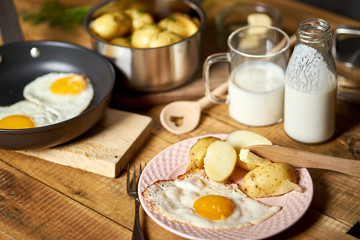 Fried egg with young potatoes with dill and milk on  wooden table