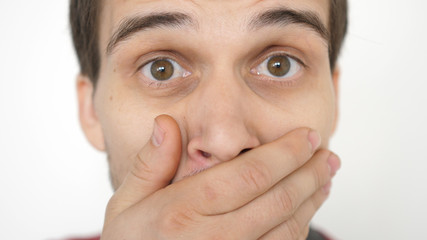 Close-up of a surprised emotional man with brown eyes looking into the camera.