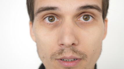 Close-up of a surprised emotional man with brown eyes looking into the camera.