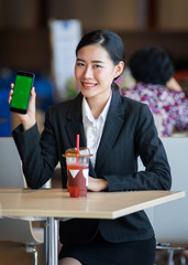 Young beautiful female wears black business suit works, shops online via cell phone and laptop with happy and smile face in department store. Business person, modern lifestyle, and shopping concept.