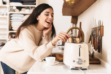 Lovely young girl having cup of coffee at the kitchen