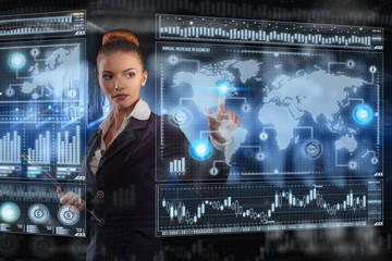 Young business lady works with virtual graphic interface in futuristic office