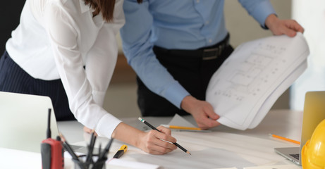 Young couple of architecture working with construction drawing