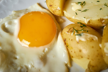 close up on fried eggs with young potatoes with butter and dill