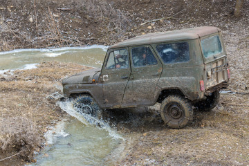 Obraz na płótnie Canvas Rally on Russian SUVs in the mud in winter, Trapped all-terrain vehicle pulled out of the river