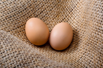 Two fresh eggs from a farm lie on a bag. Healthy food
