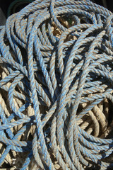 coils of used and grungy nylon blue lobster trap rope vertical