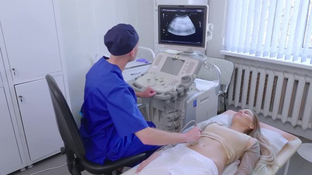 Doctor makes an ultrasound examination of lying woman