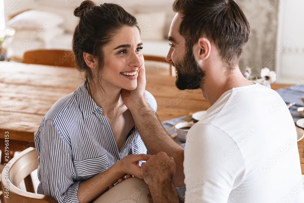 Sticker Photo of tender brunette couple in love smiling while hugging together in apartment