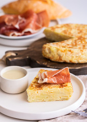  Tortilla,  Spanish omelette made with eggs and potatoes. Traditional Spanish tapa served with mayonnaise  and jamon, Iberian ham on white background.