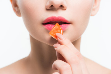 cropped view of woman holding orange jelly candy isolated on white