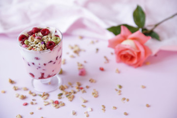 Obraz na płótnie Canvas yogurt parfait with fresh raspberry berries and rose on a light pink background. Healthy food. With copy space for text.