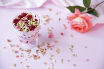 yogurt parfait with fresh raspberry berries and rose on a light pink background. Healthy food. With copy space for text.