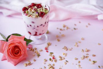 yogurt parfait with fresh raspberry berries and rose on a light pink background. Healthy food. With copy space for text.