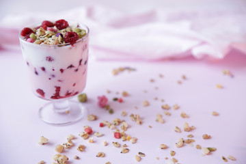 yogurt parfait with fresh raspberry berries on a light pink background. Healthy food. With copy space for text.