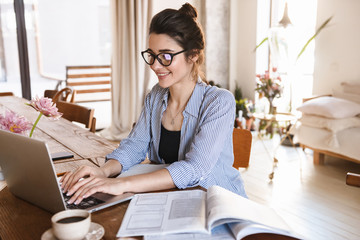 Image of smart positive woman typing on laptop while working or studying at home