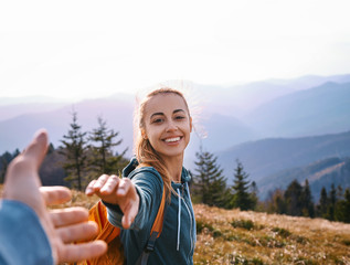 happy attractive woman hiker standing on the mountain slope against background of sunset. Traveling and follow me concept. - obrazy, fototapety, plakaty