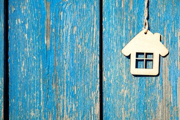 The symbol of the house hangs on a blue wooden background 