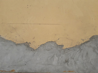 The wall made of damaged cement has been repaired with a new cement plaster from the original wall painted yellow.
